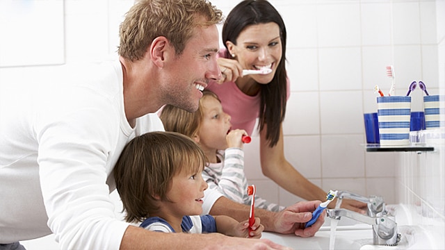 Family brushing teeth with kids mouthwash nearby 