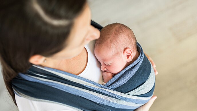 new mother holding her baby, highlighting bleeding gums during pregnancy 