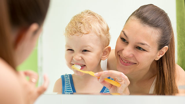 mother brushing toddler's teeth to prevent white spots on children's teeth