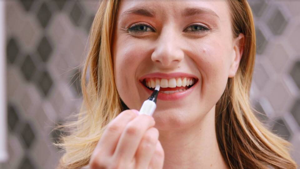 young woman applying the serum on her teeth