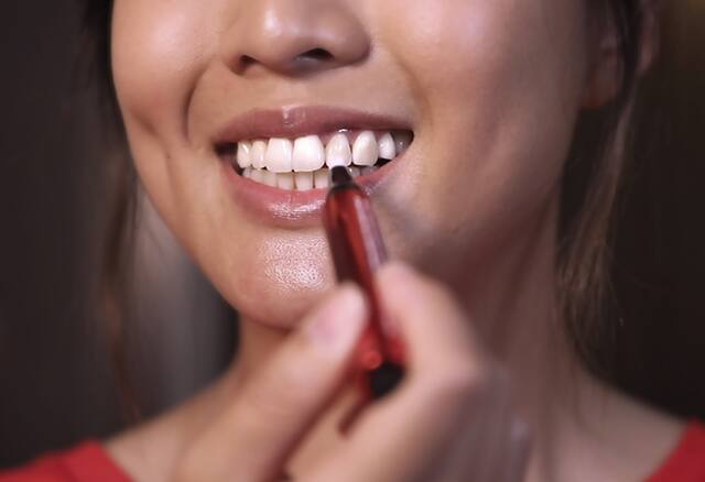 Lady applying serum pen to teeth 