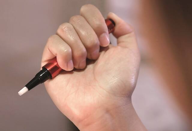 Lady applying whitening pen to teeth Lady holding serum pen