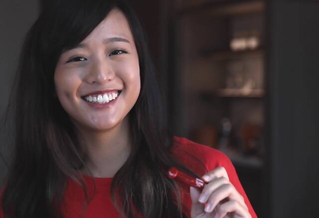 Woman smiling holding whitening pen 