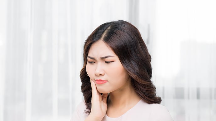 woman holding jaw due to tooth pain