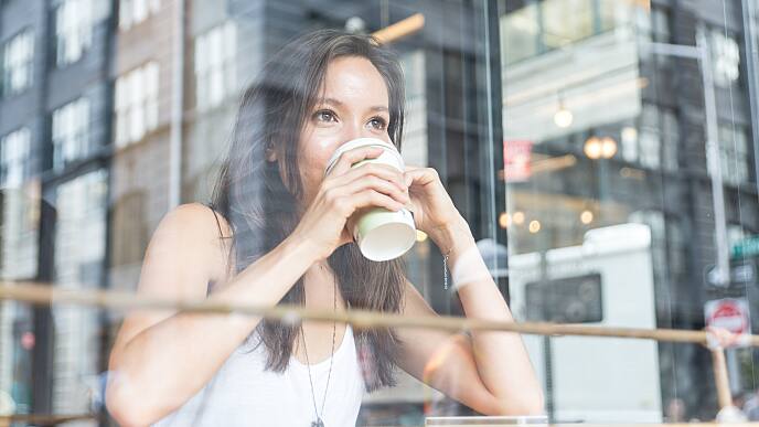 a woman is drinking tea and thinking how to treat black teeth stains