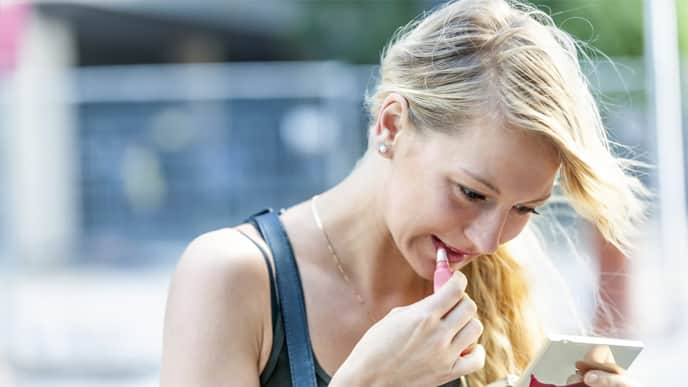 a girl is applying the right lipstick that makes her teeth look whiter 