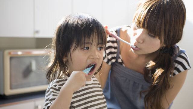 mother and daughter are brushing teeth together with whitening toothpaste