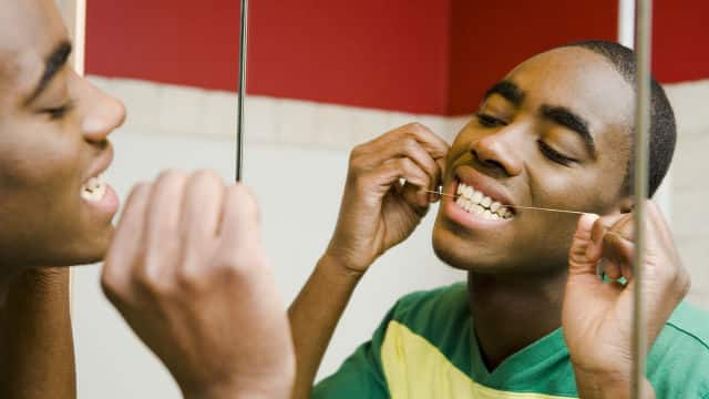 young boy is using interdental brush to floss teeth