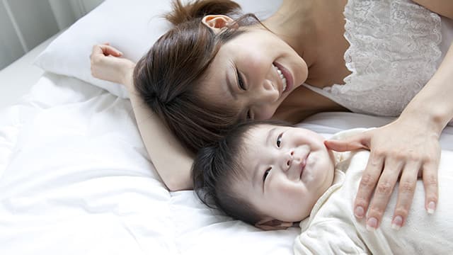 Teething Baby Smiling With Mother in Bed