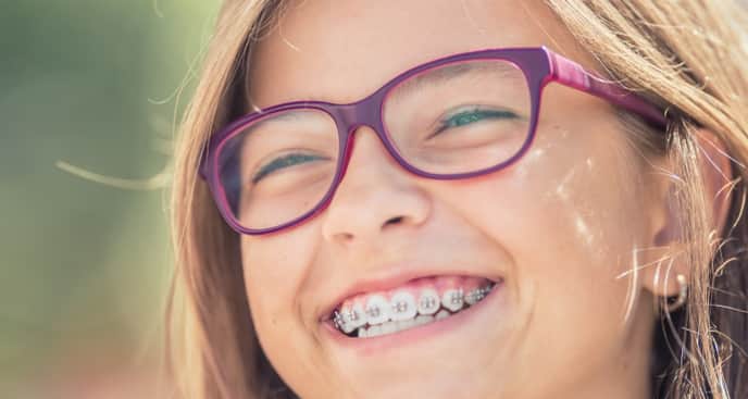 Portrait of a happy smiling teenage girl with dental braces and glasses; image used for best Methods for Keeping Teeth White With Braces: Get Glowing Results