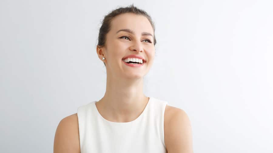 Young woman smiling against white background; image for Hydrogen Peroxide for Teeth Whitening: Does it Work and is it Safe article